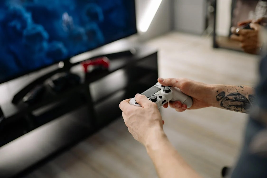 Someone sat in front of a TV holding a gaming controller.