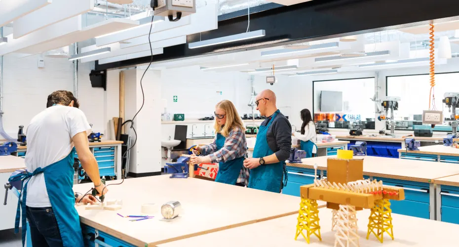 diverse group of individuals collaborating in an engineering makerspace workshop at exeter focused on hands-on projects.